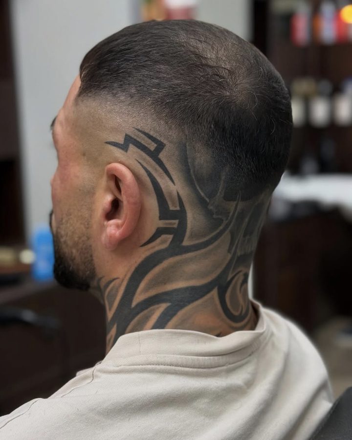 Kurzer Fade von hinten, Kunde mit großem Tribal-Tattoo an Hinterkopf und Nacken