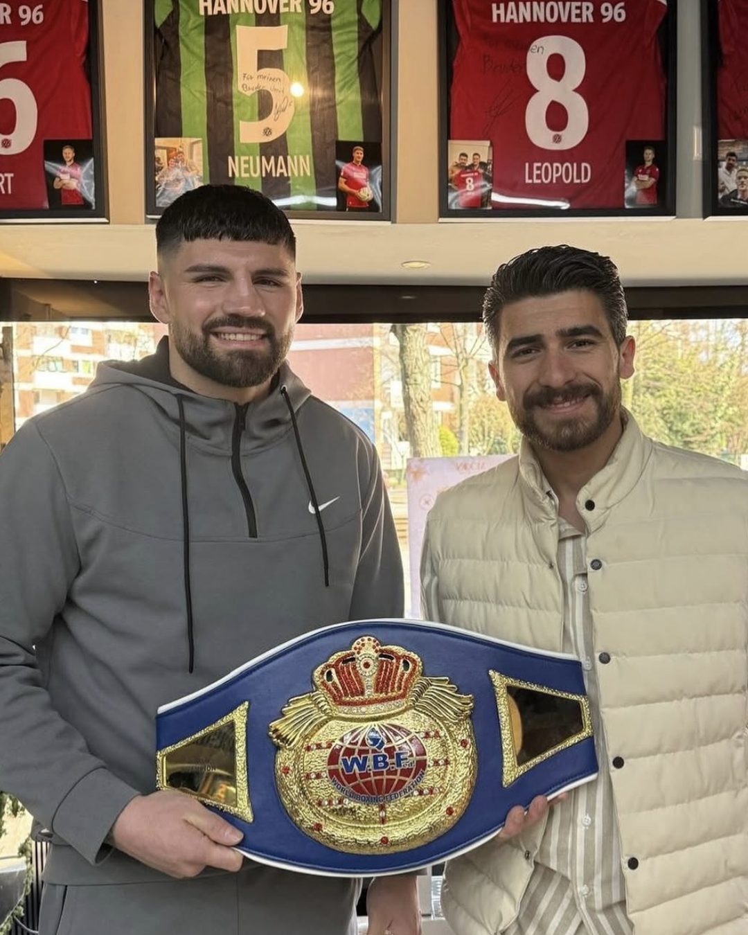 Ümit Koç und Profiboxer Artur Mann mit Titelgürtel im Barbershop KOÇ