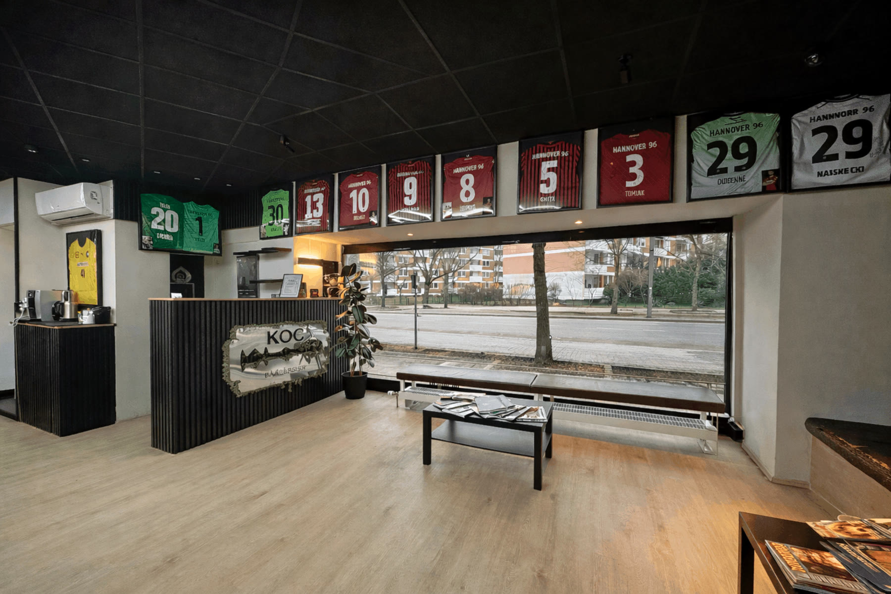 Blick zur Fensterfront des Barbershop KOÇ, darüber gerahmte Trikots